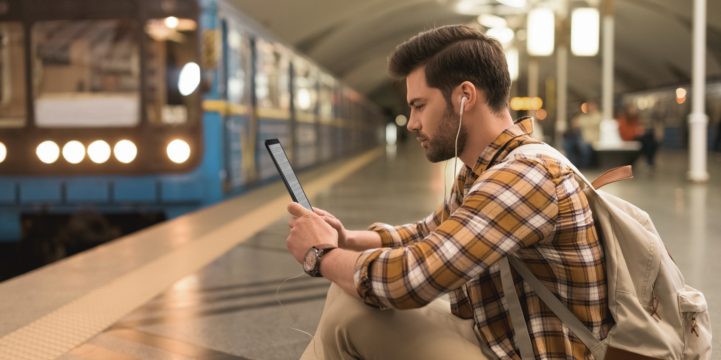 boy reading at the train station on e-book reader inkBOOK