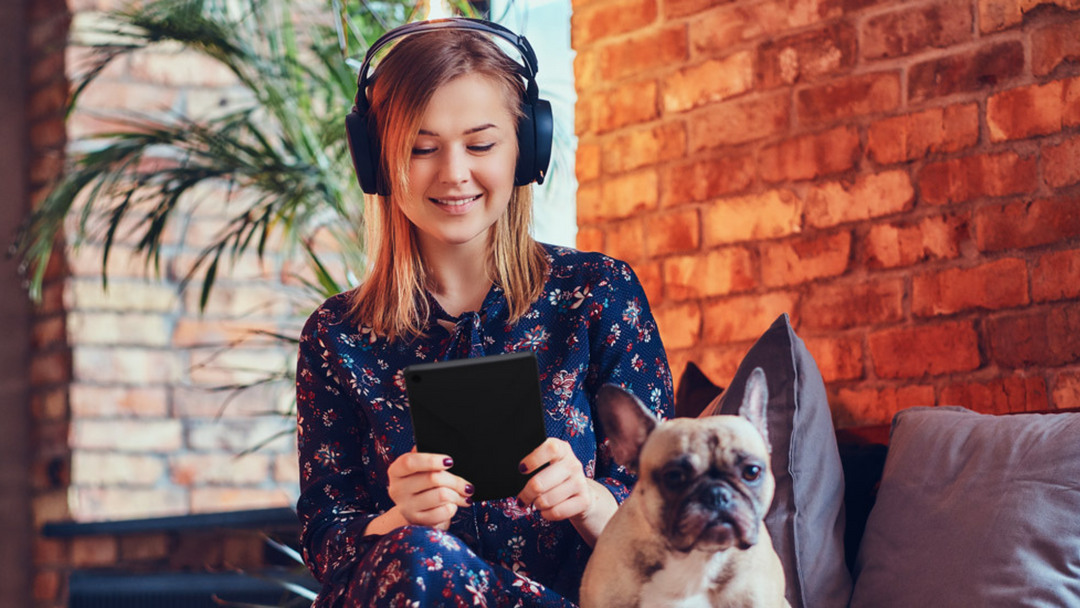 gril reading on the e-reader with a dog next to her